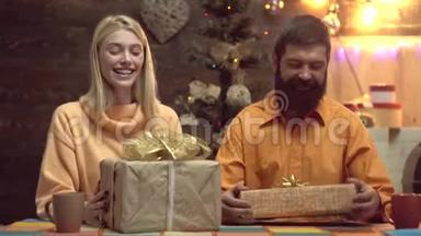 可爱的一对夫妇在家里打开圣诞礼物。 年轻夫妇把圣诞礼物包装成纸。 <strong>送礼</strong>物。 微笑